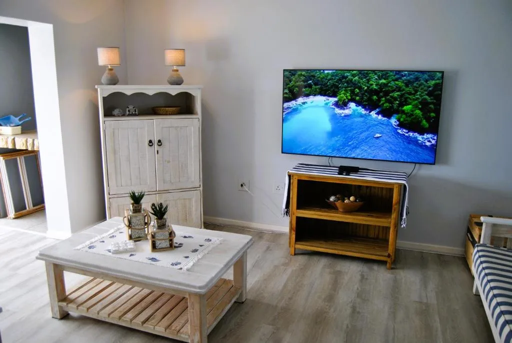 Bright lounge with TV, wooden storage cabinet, and coastal décor accents