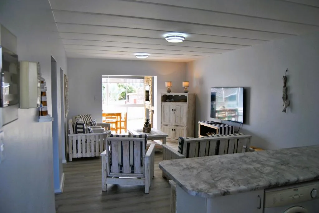 Open-plan lounge with striped armchairs, TV, and ocean view doors