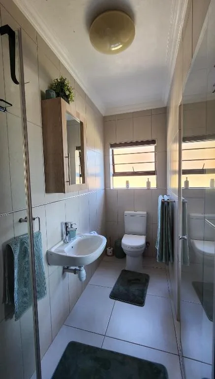 Bright bathroom with vanity sink, toilet, shower enclosure and round ceiling light