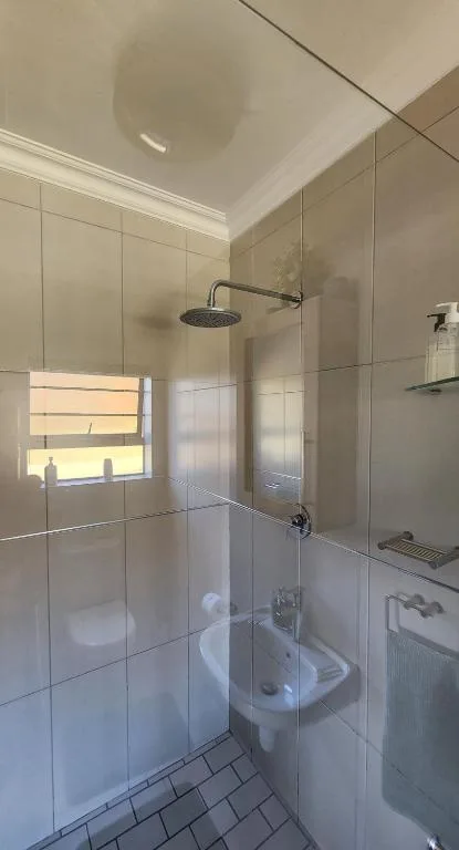 Modern bathroom with walk-in shower, rainfall showerhead, and tiled walls