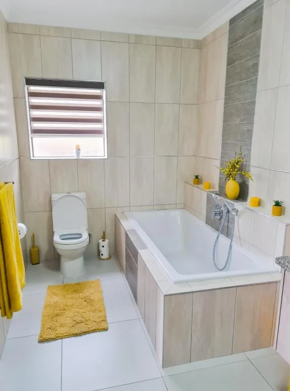 Modern bathroom with bathtub, toilet, and yellow decorative accents