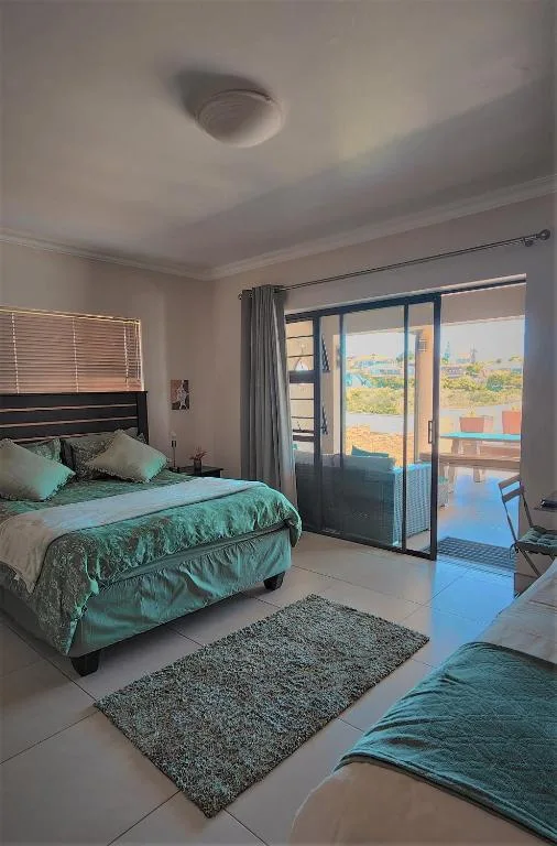 Spacious bedroom with turquoise bedding and sliding glass doors to deck