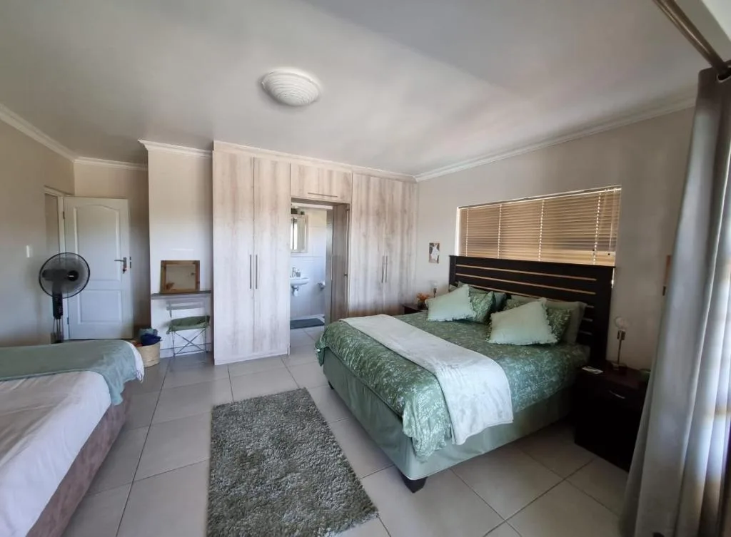 Spacious bedroom with queen bed, green bedding, and en-suite bathroom access