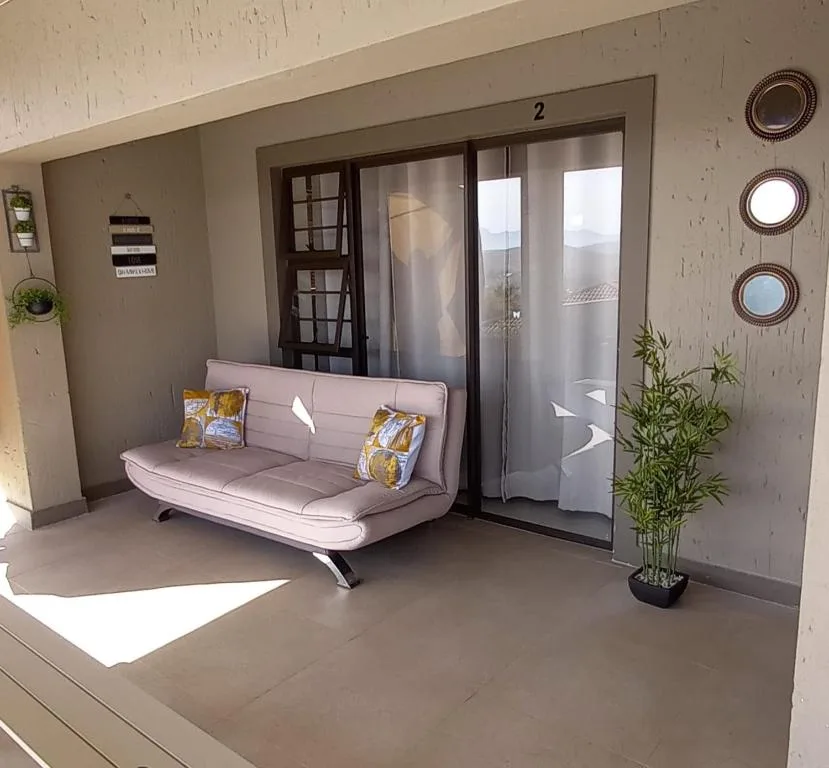 Covered patio with modern grey sofa and potted bamboo plant overlooking garden
