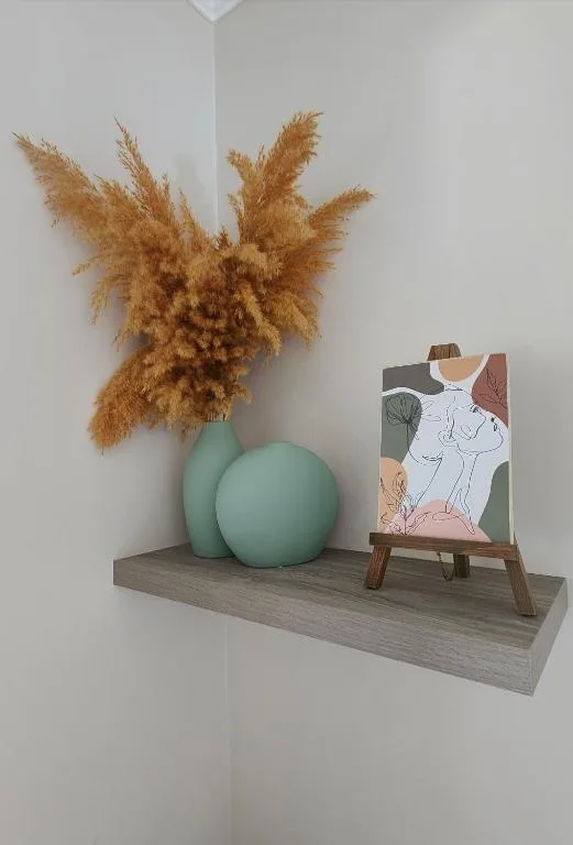 Decorative shelf with dried pampas grass, mint sphere, and minimalist artwork