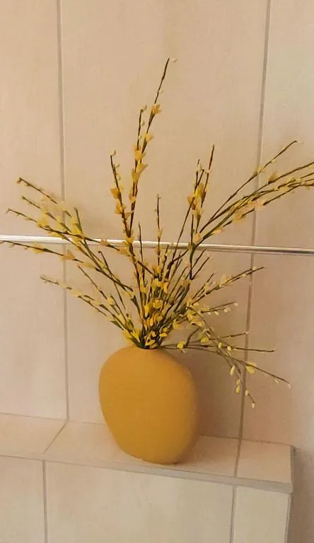 Golden dried grasses and wheat in mustard-colored vase on shelf