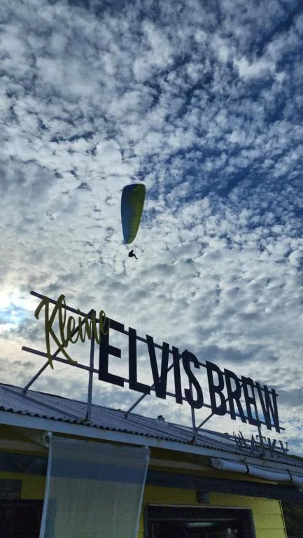 Paraglider soaring above signage with dramatic cloudy sky backdrop