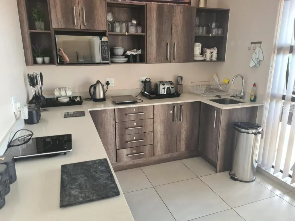 Modern kitchen with wooden cabinetry, stainless steel appliances, and white countertops