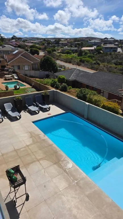 Sparkling blue swimming pool with loungers overlooking Garden Route suburb