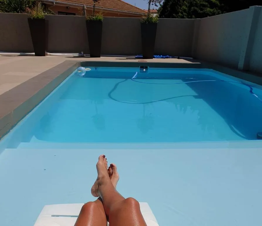 Sparkling blue swimming pool with lounging guest and enclosed patio area