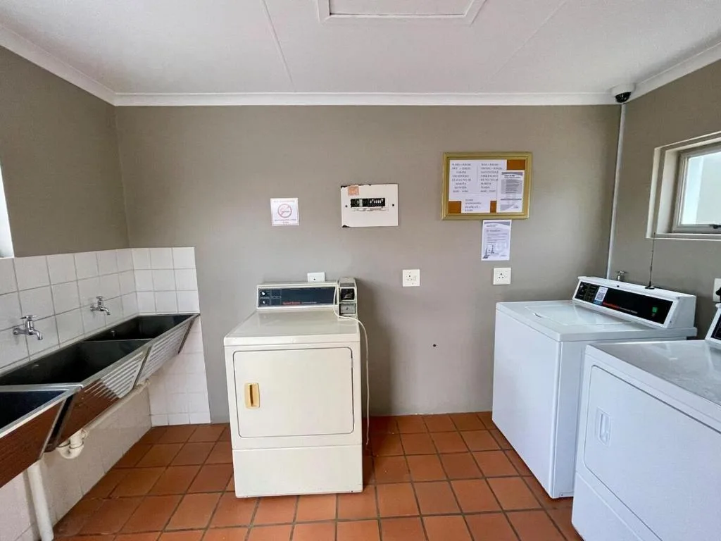 Shared laundry room with washing machine, dryer, sink, and instruction boards