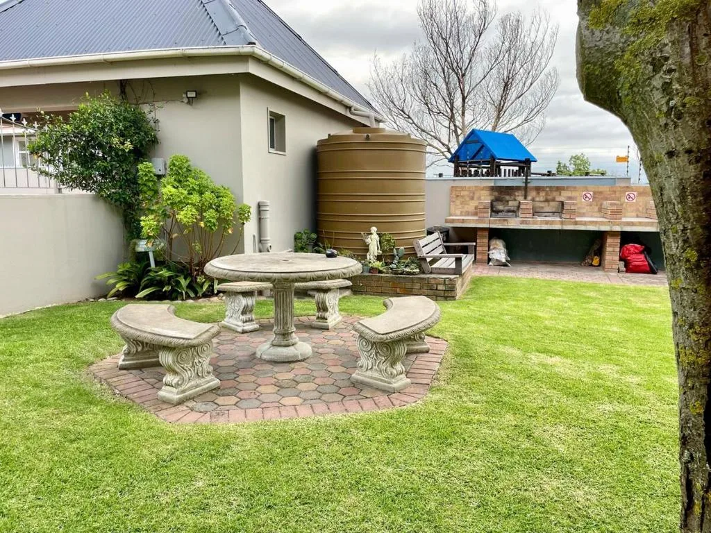 Manicured garden with stone seating area and water tank beside property