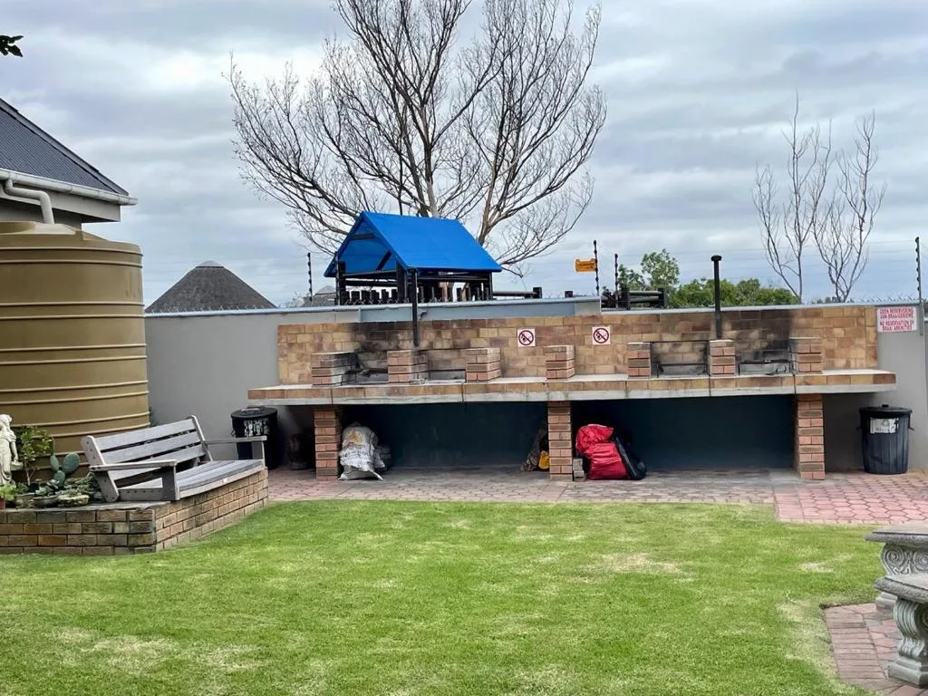 Brick braai area with blue roof structure set in manicured garden