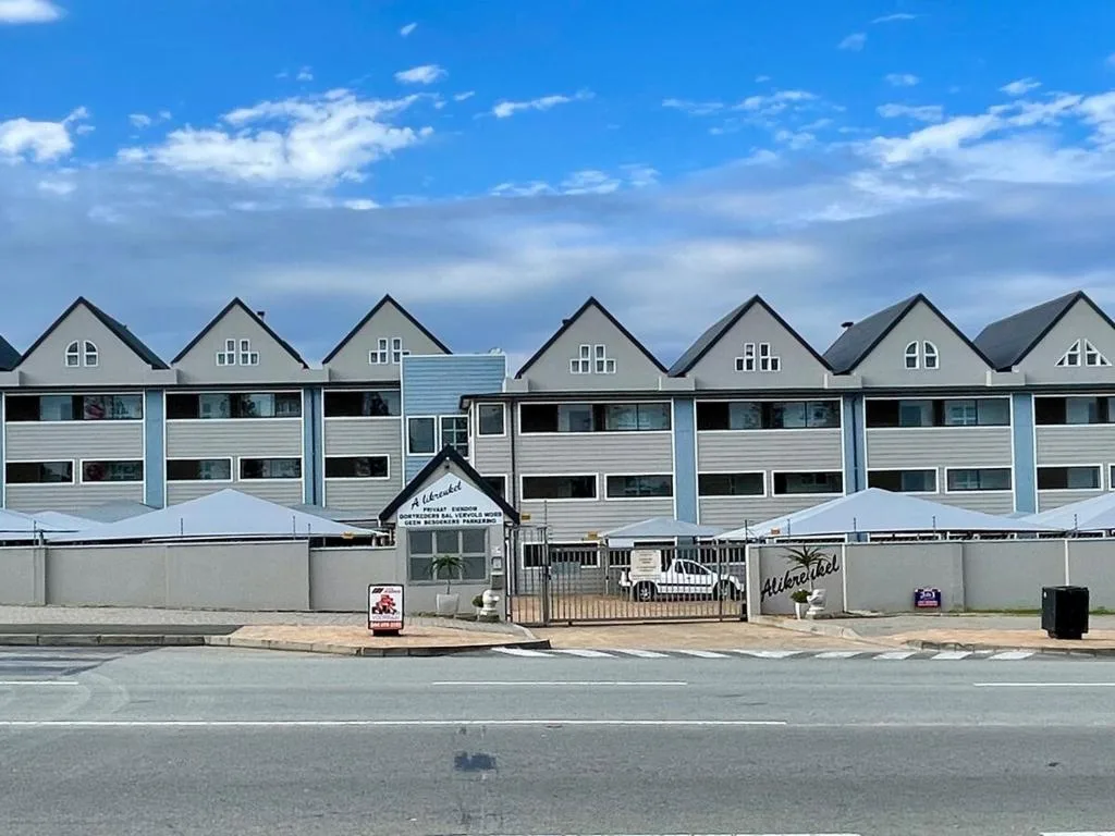 Beachfront row of modern white apartment units with peaked roofs and large windows