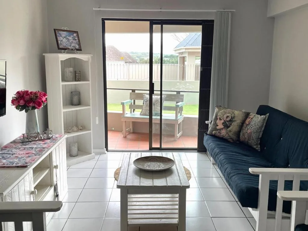 Bright lounge with sofa, decor shelving, and garden view doors