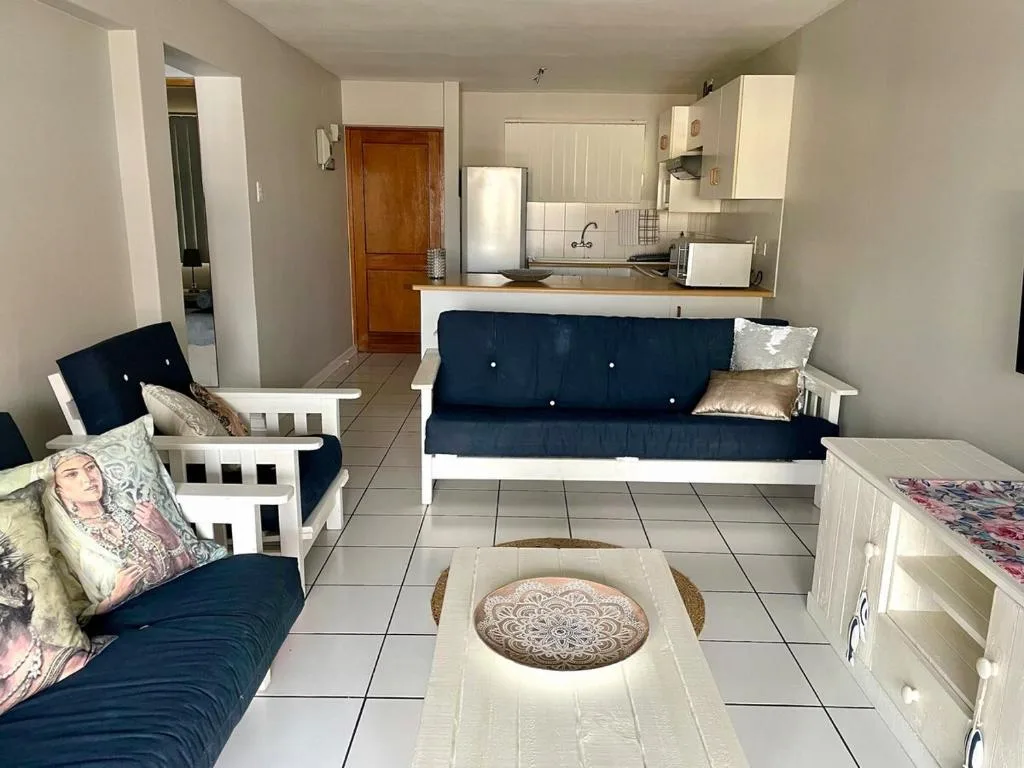 Open-plan lounge with navy sofa, armchairs, and kitchen visible in background