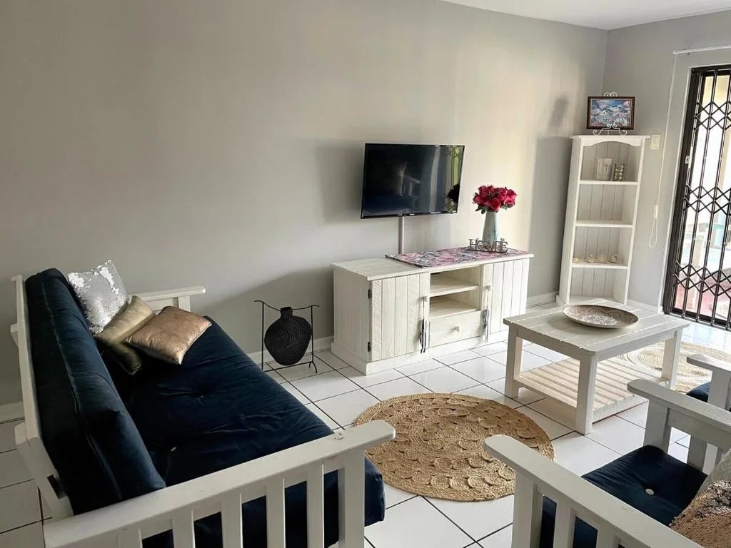 Bright living room with navy sofa, wall-mounted TV, white shelving unit