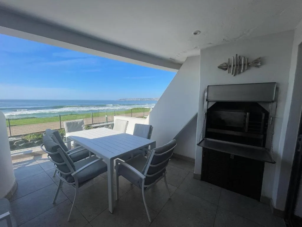 Oceanfront deck with dining table, chairs, and panoramic sea views