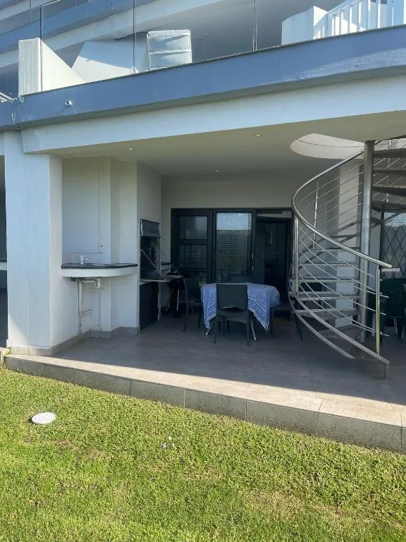 Modern patio with outdoor seating, kitchenette, and spiral staircase access
