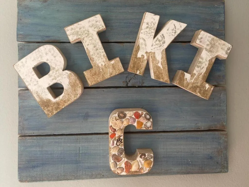 Rustic wooden sign spelling Bikle with shell decorations, property signage