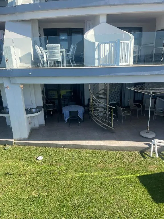 Modern white apartment building with upper and lower deck areas, green lawn