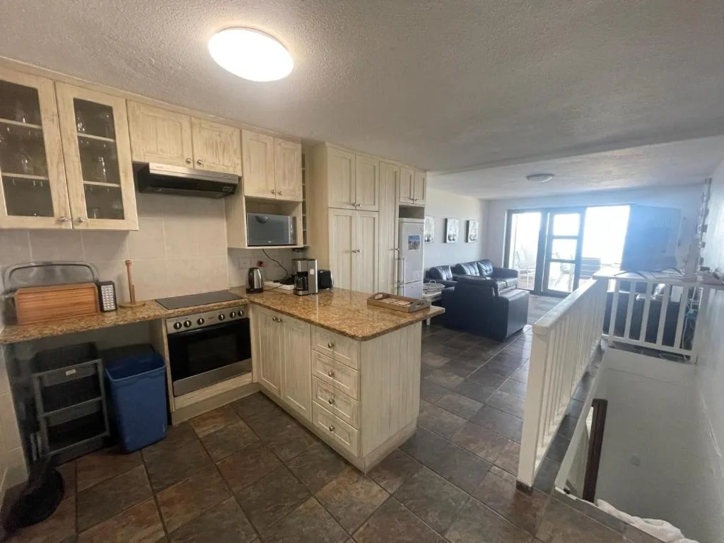 Spacious kitchen with cream cabinetry, granite countertop island, and stainless steel appliances
