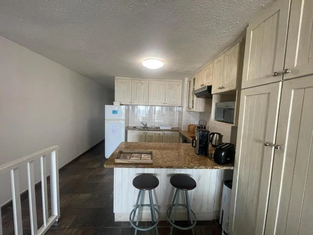 Light wood kitchen with island counter, bar seating, and modern appliances