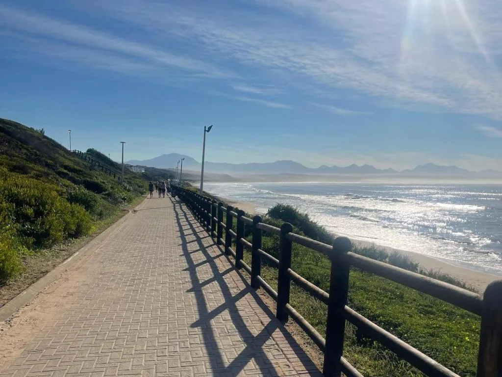 Coastal promenade overlooking pristine beach with mountains in distance
