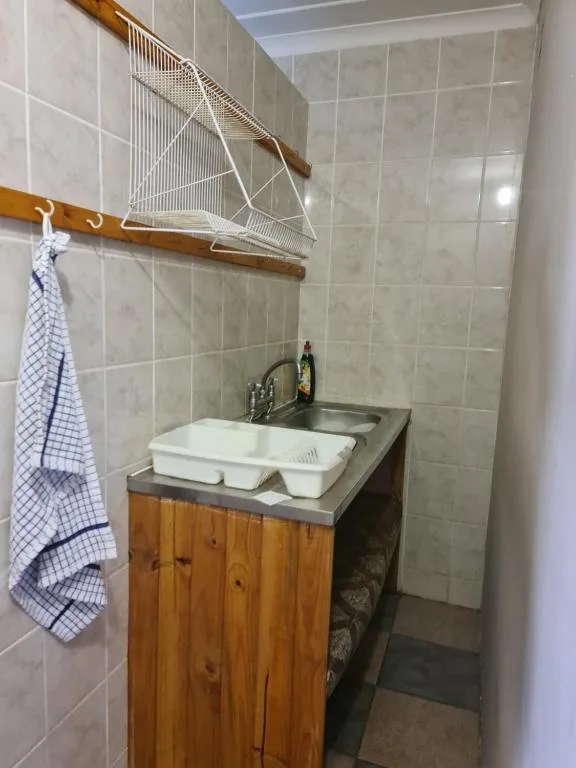 Bathroom vanity with white basin and wooden cabinet under tiled walls
