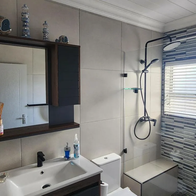 Modern bathroom with double sink vanity, walk-in shower and striped tile accent wall
