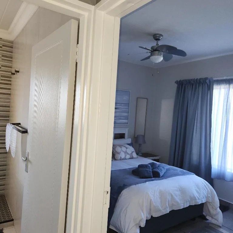 Spacious bedroom with double bed, ceiling fan, and ocean view curtains