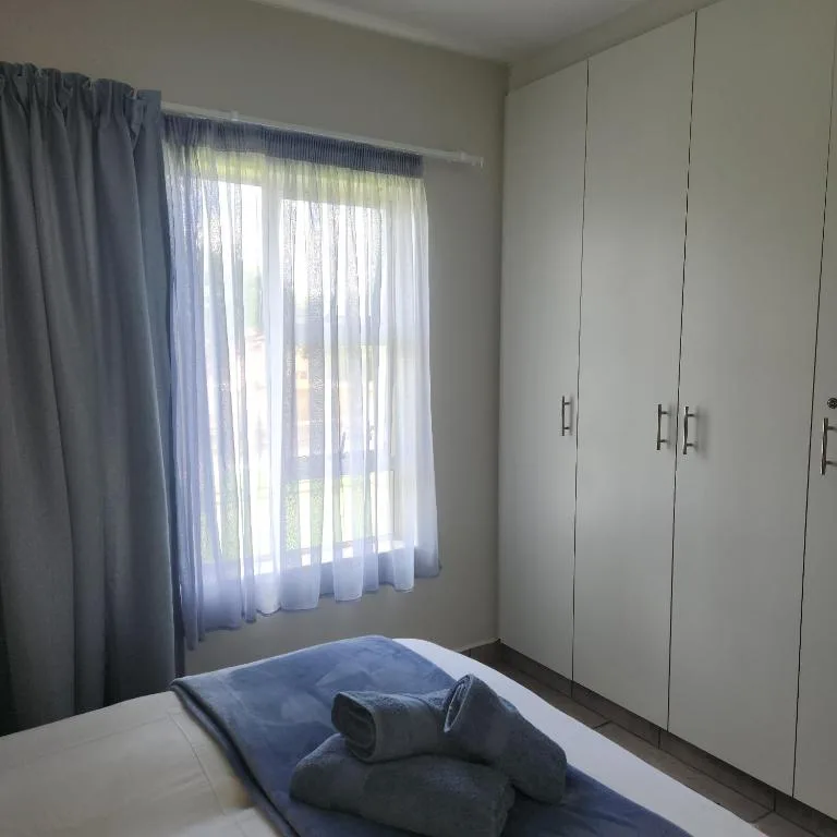 Bright bedroom with built-in wardrobes and sheer window curtains