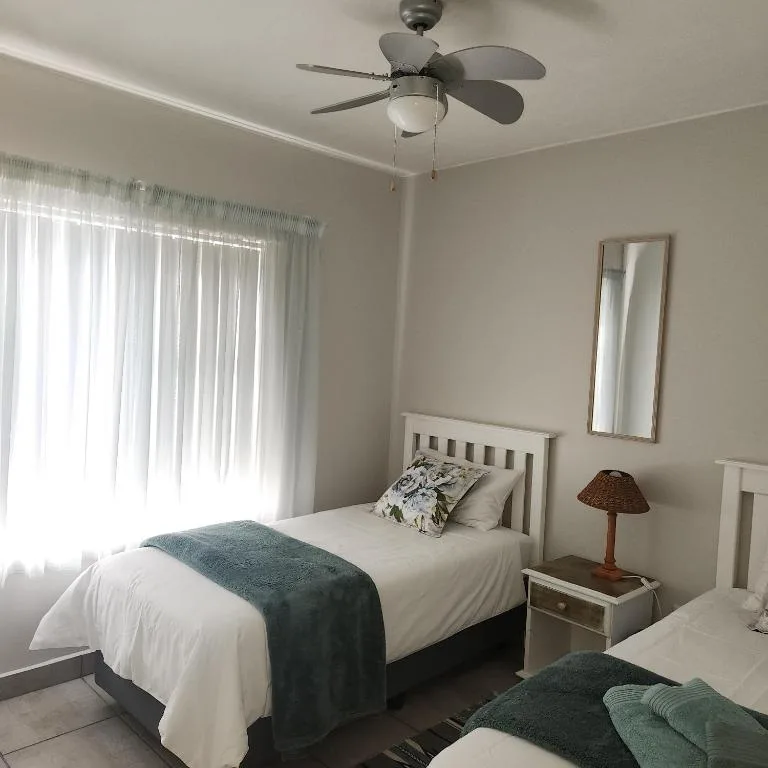 Bright bedroom with single bed, ceiling fan, and sheer curtains