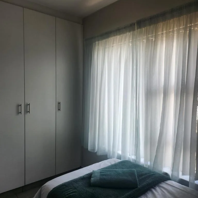 Bright bedroom with white built-in wardrobe and sheer curtains