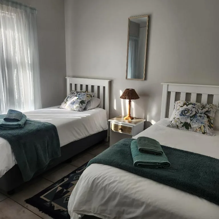 Bright twin bedroom with white headboards, green throws, and natural light