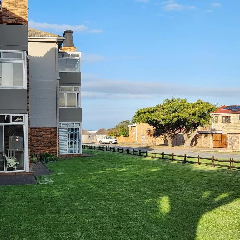 Modern apartment building with manicured lawn and black fencing, bright sunny day