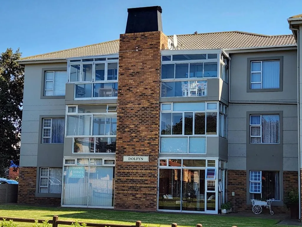 Modern multi-story apartment building with brick chimney and large windows