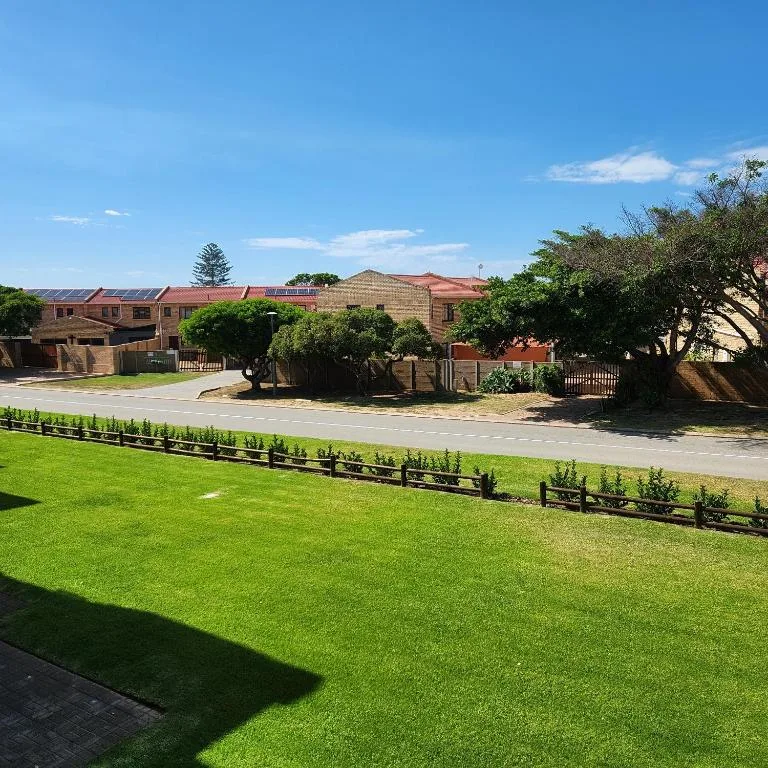 Brick property with manicured lawn, wooden fence, and driveway entrance