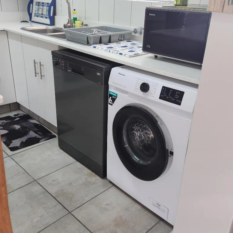 Modern kitchen with dishwasher, washing machine, and stainless steel sink