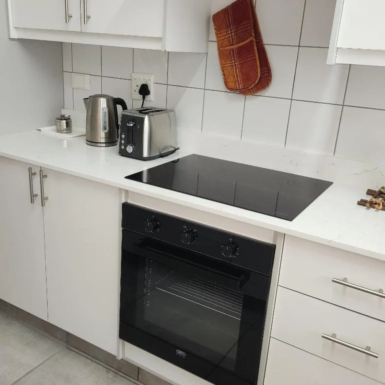 Modern kitchen with white cabinetry, black induction cooktop, and stainless steel kettle