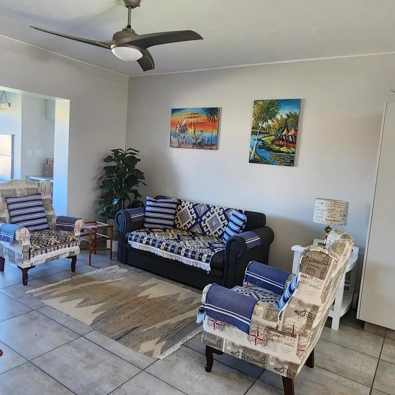 Bright lounge with blue striped sofa, ceiling fan, and coastal artwork