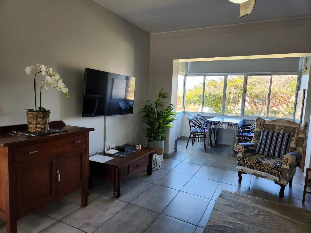 Spacious lounge with TV, comfortable seating, and large windows overlooking garden