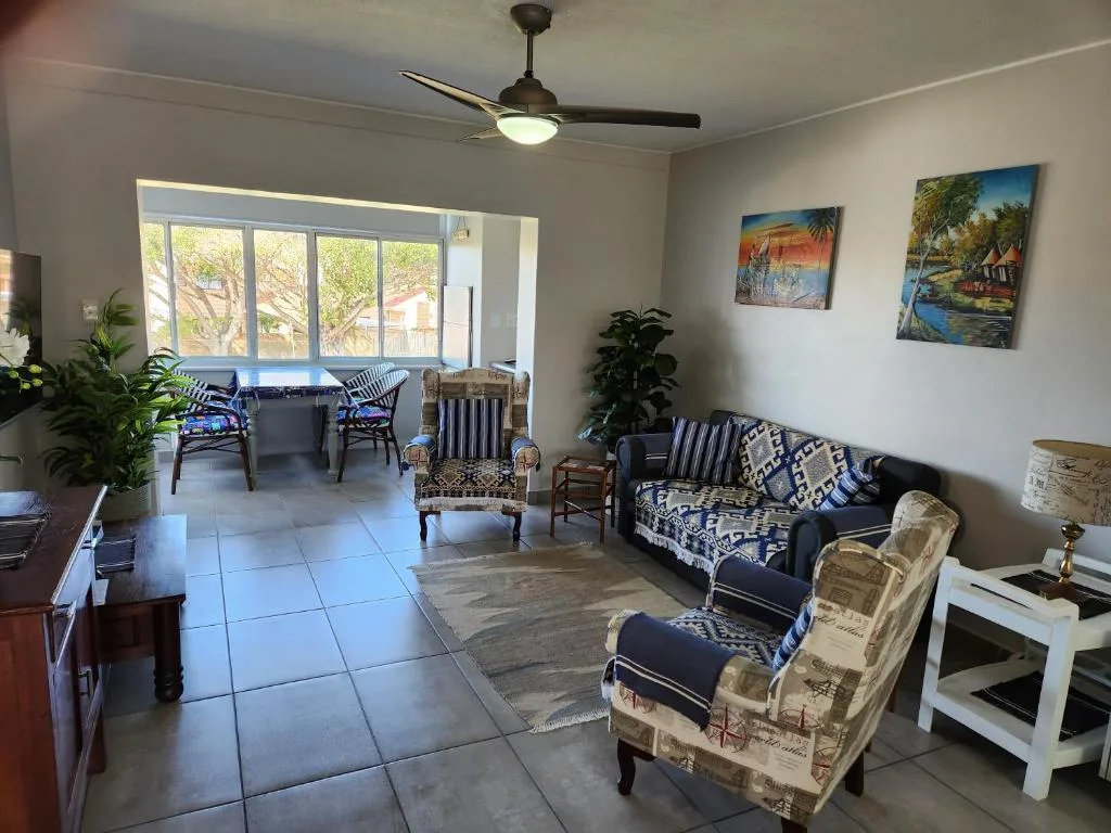 Spacious living room with sofa, armchairs, ceiling fan, and garden views