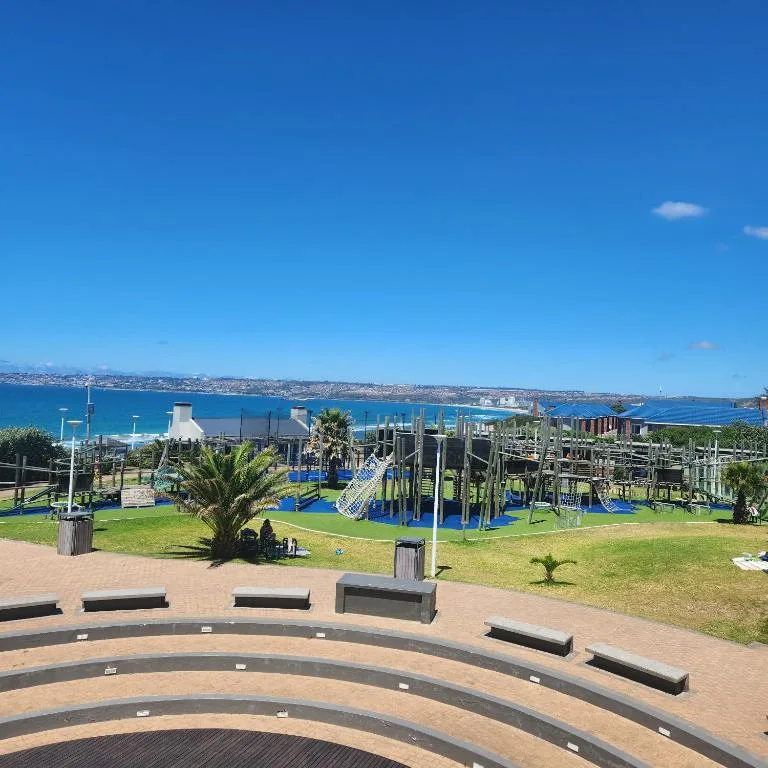 Scenic coastal view with ocean, mountains, and playground area beyond