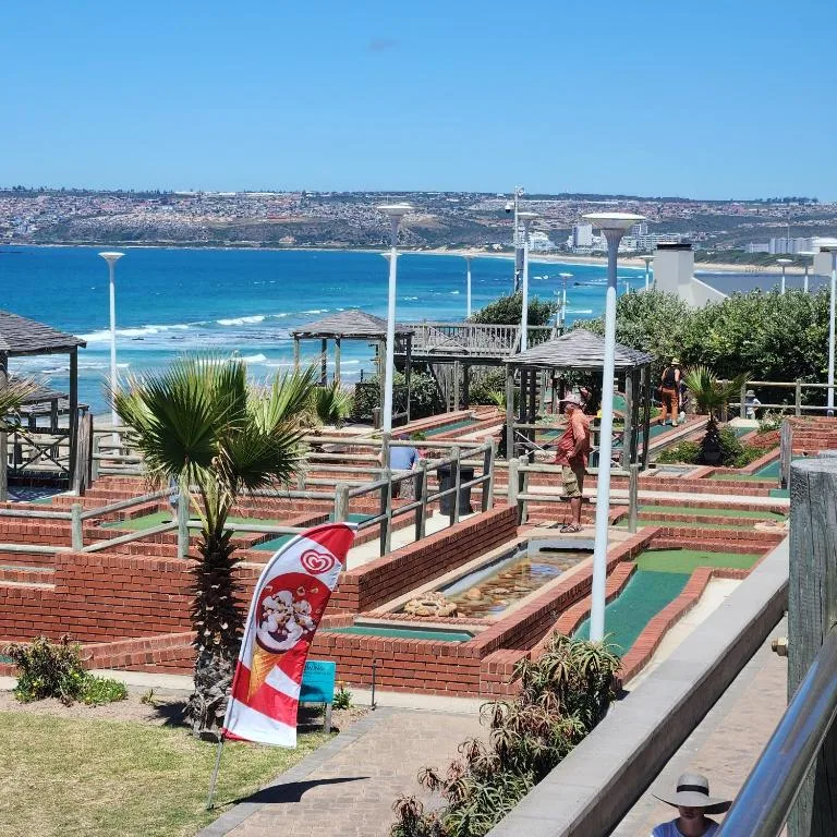 Turquoise ocean and coastal town visible beyond mini golf course