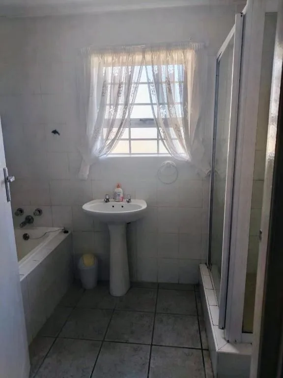 Bright bathroom with pedestal sink and bathtub featuring natural light