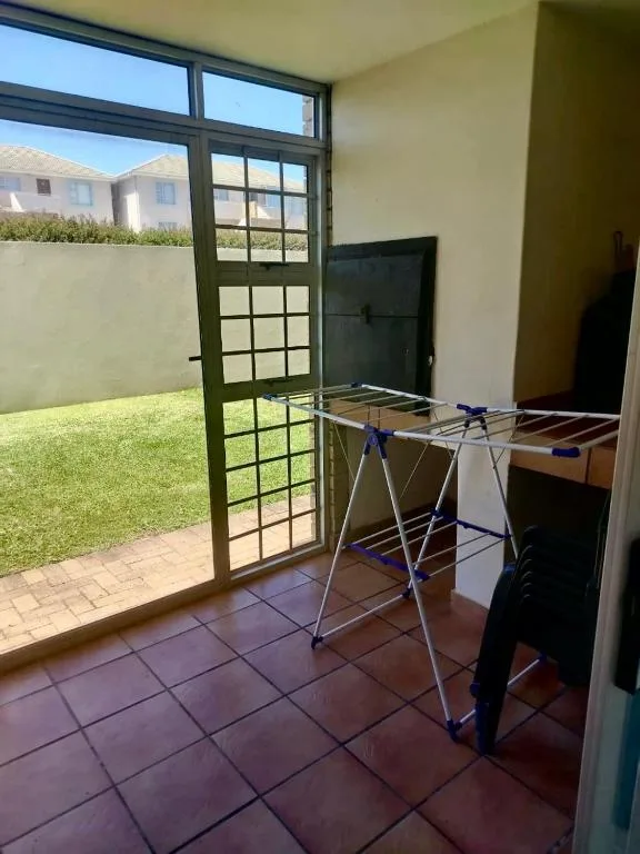 Indoor laundry area with clothesline and garden view through glass doors