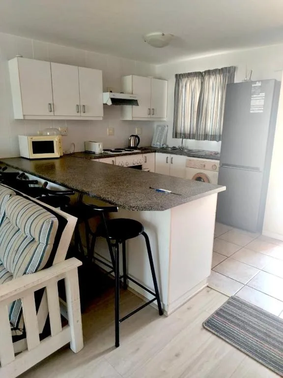 Modern kitchen with white cabinetry, granite countertop, and breakfast bar seating