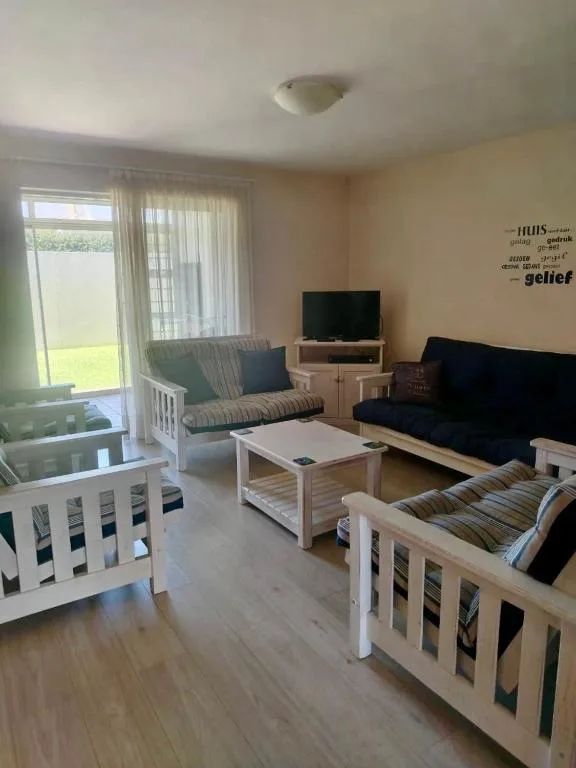 Bright living room with sofas, TV, and access to garden via glass doors