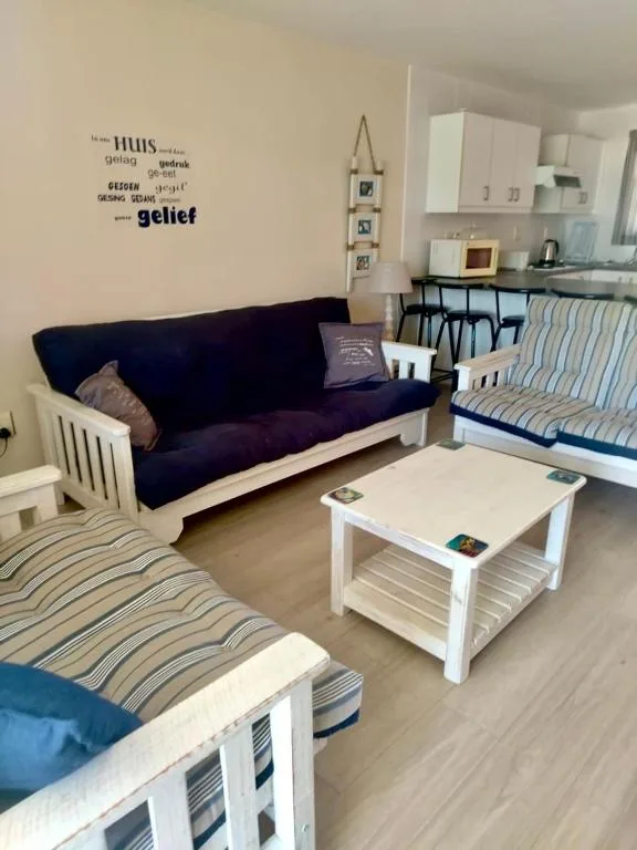 Open-plan lounge with navy sofa, white futon, and wooden coffee table